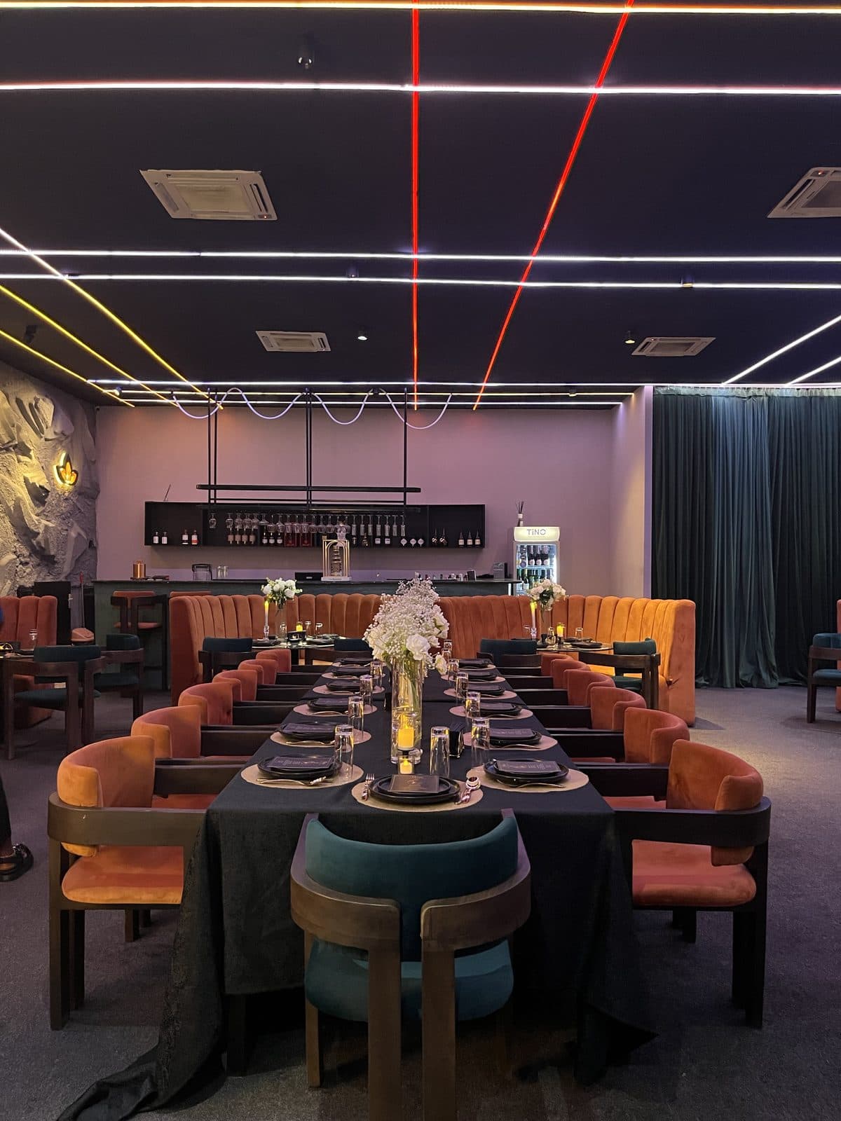 LYA Restaurant — the dining room, long table set beneath neon lines