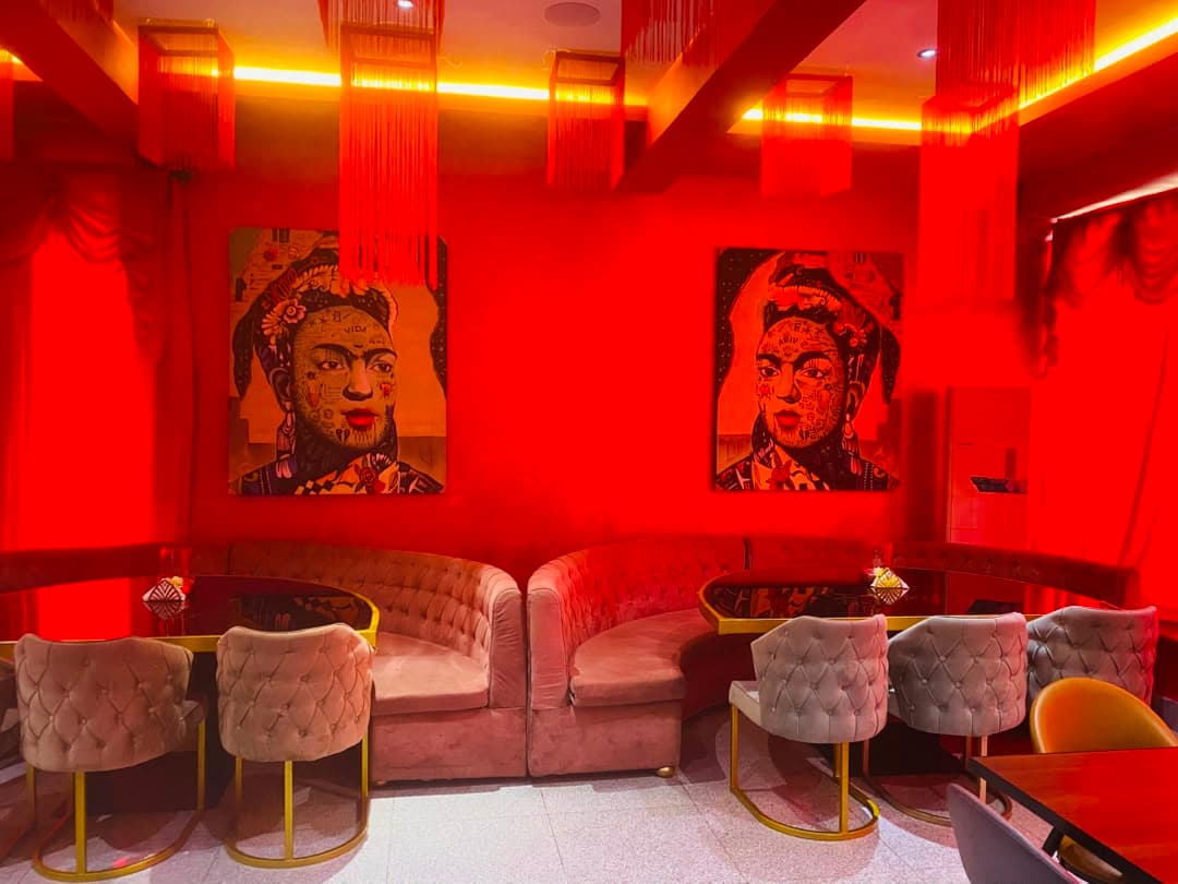 Tokyo by LYA — the dining room under red light, banquette seating and portrait art