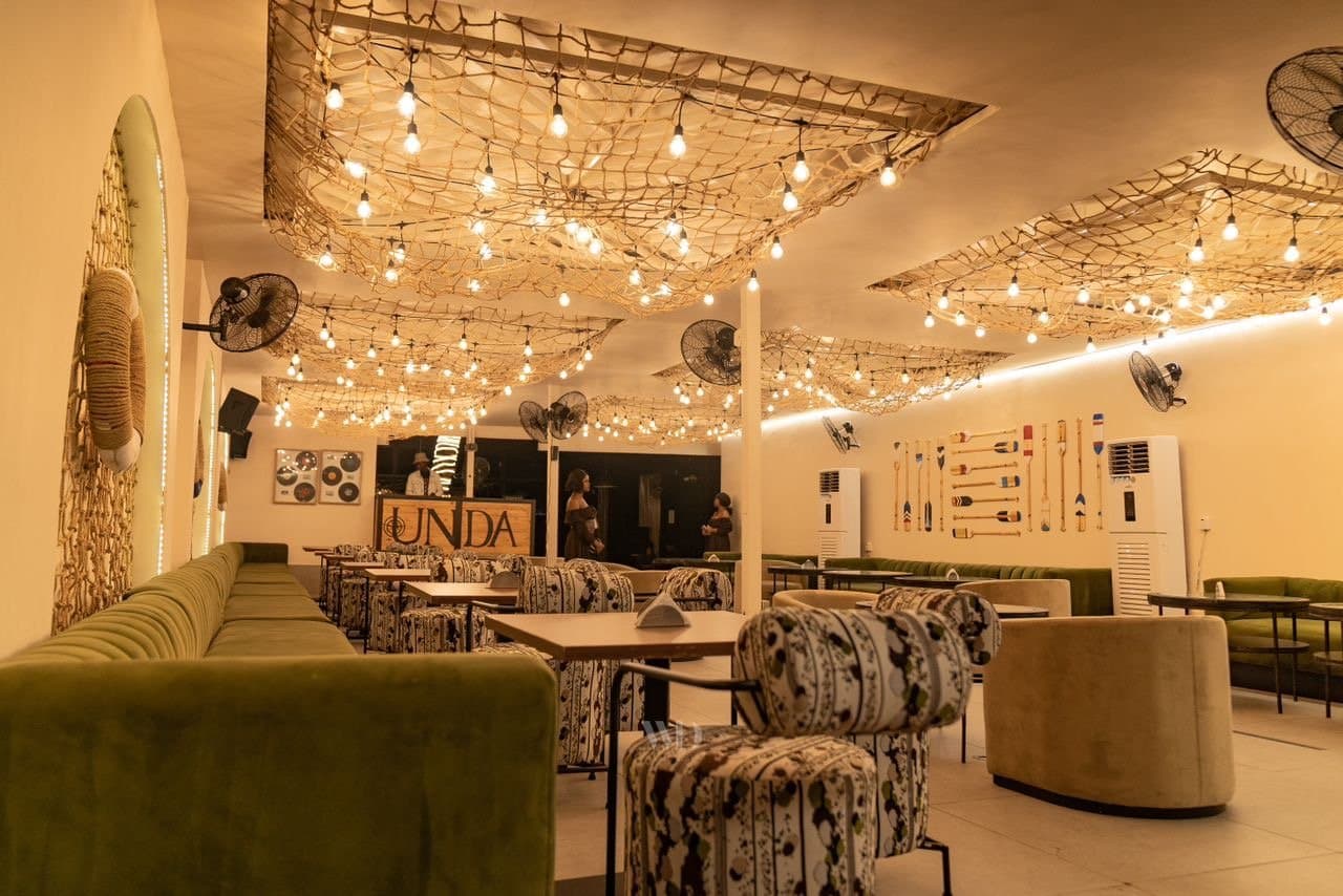 Unda by LYA — the room under fishnet-and-festoon ceiling lights